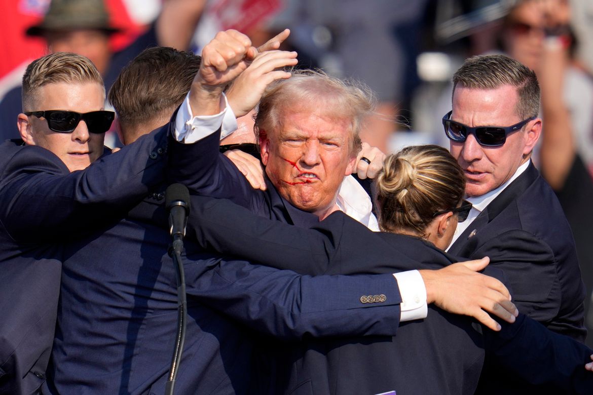 Donald Trump pumps his fist as he is helped off the stage. (Gene J. Puskar/Associated Press)